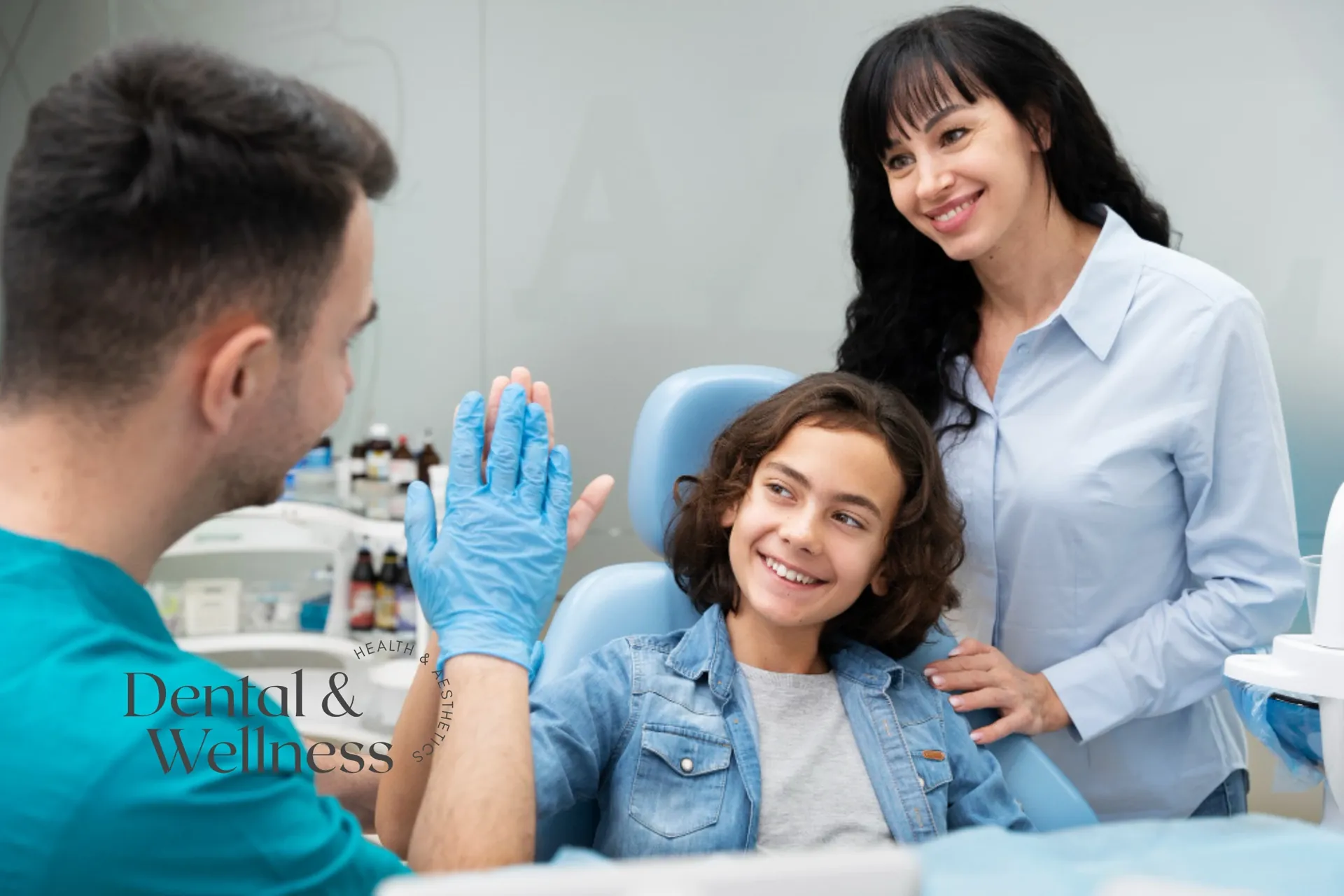 Dentist high-fiving a young patient in the chair as his mother looks on
