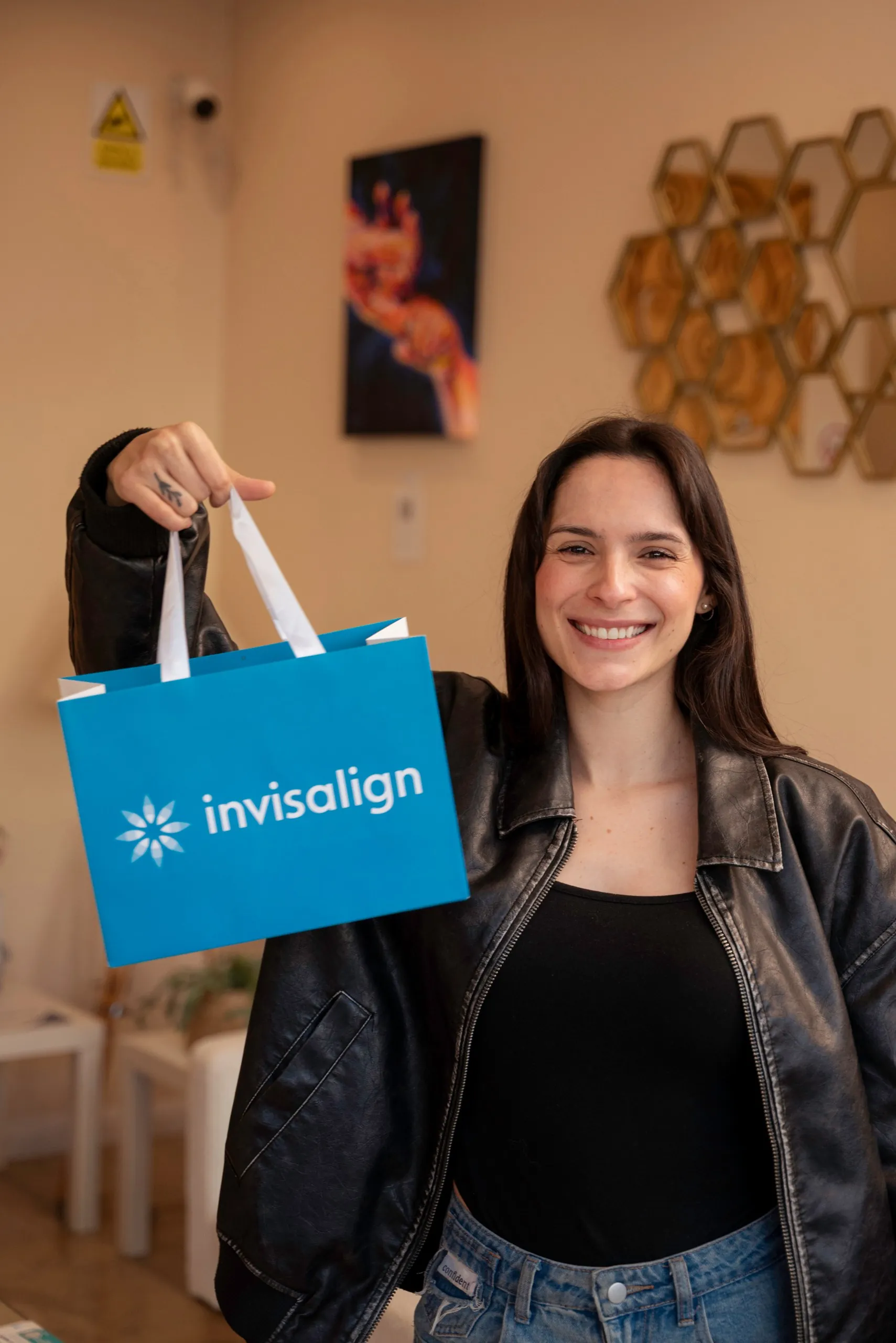 Patient holding up an Invisalign bag in the clinic reception — Invisalign for overbite treatment