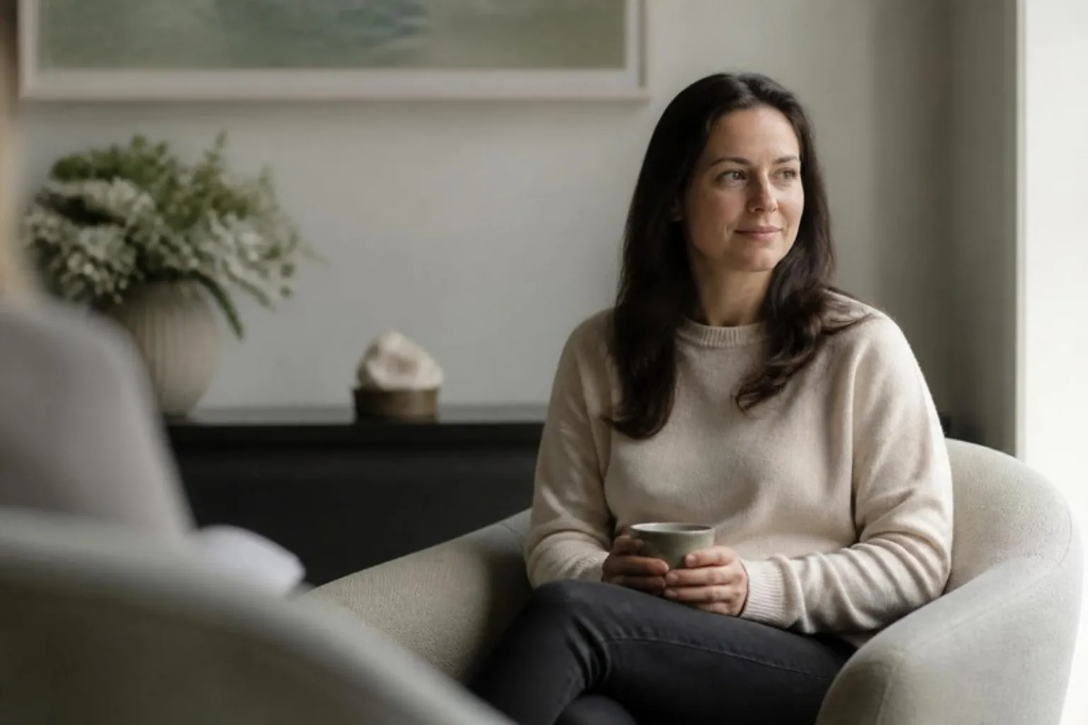 A nervous patient relaxing in a calm clinic lounge holding a cup of tea