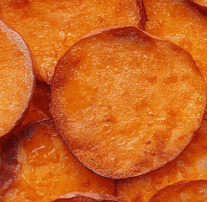 Nahaufnahme von goldbraun gerösteten Süßkartoffelscheiben mit knusprigen Rändern.