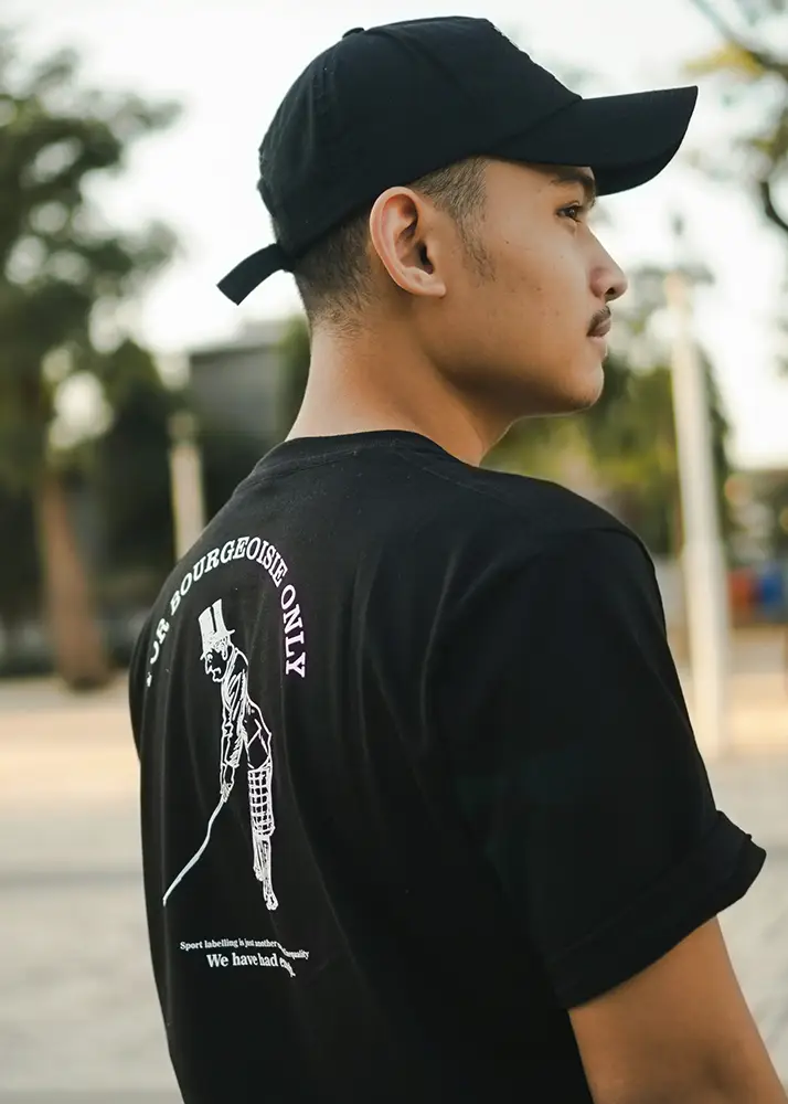 A woman is at a technology trade fair, wearing a T-shirt with a company logo printed on it, and is smiling as she looks at the design