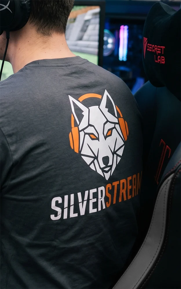 A woman is at a technology trade fair, wearing a T-shirt with a company logo printed on it, and is smiling as she looks at the design