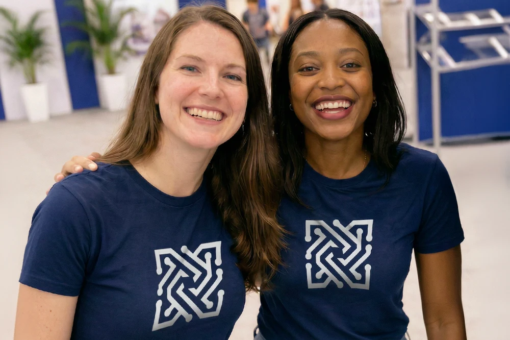 Employees from a company, wearing trade fair uniforms, are at a trade fair and are talking to a potential customer