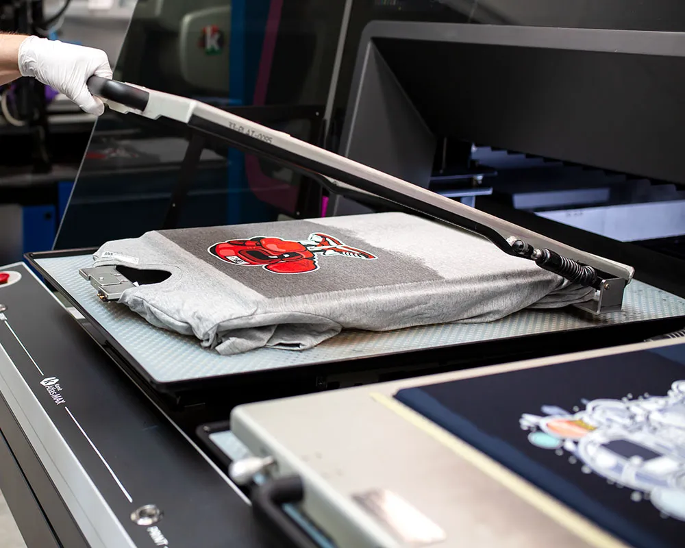 Textildruckmaschine bei der Veredelung von T-Shirts in der Prinovia-Produktion