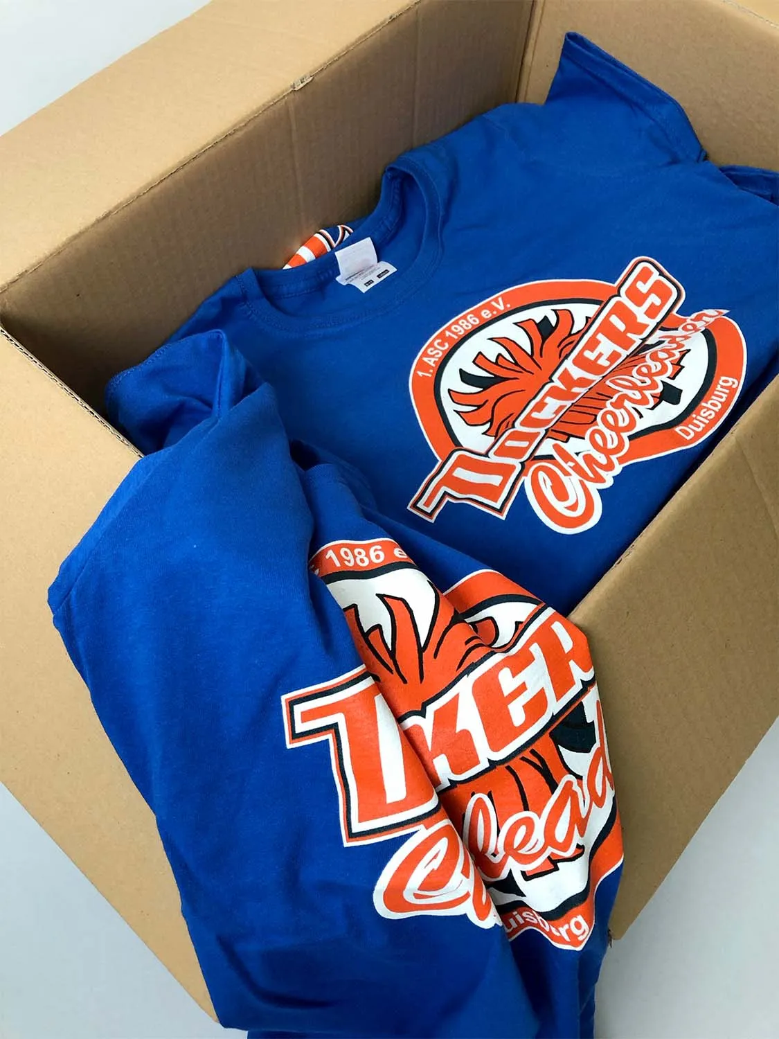Blaue Vereins-T-Shirts mit Cheerleader-Logo im Versandkarton – Großbestellung für Sportvereine