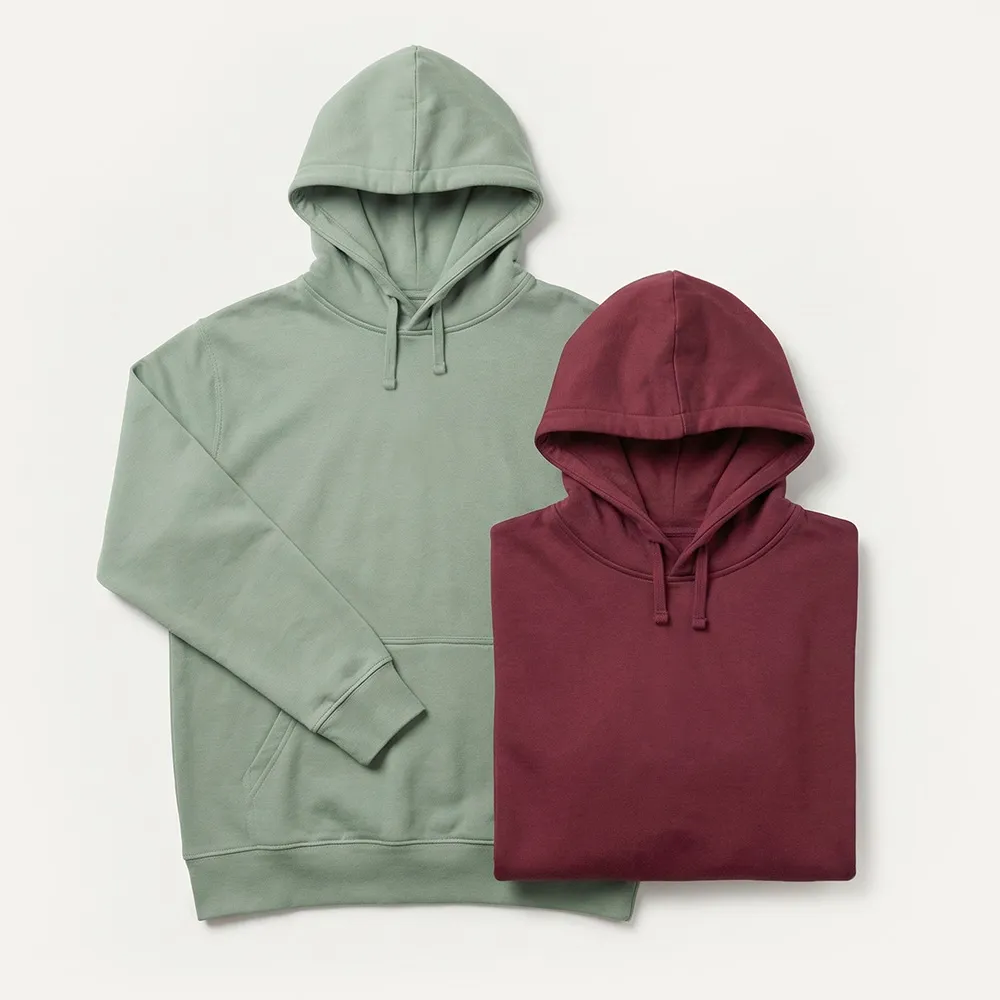 Zwei Hoodies, einer in Salbeigrün und einer in Weinrot gefaltet, auf weißem Hintergrund.