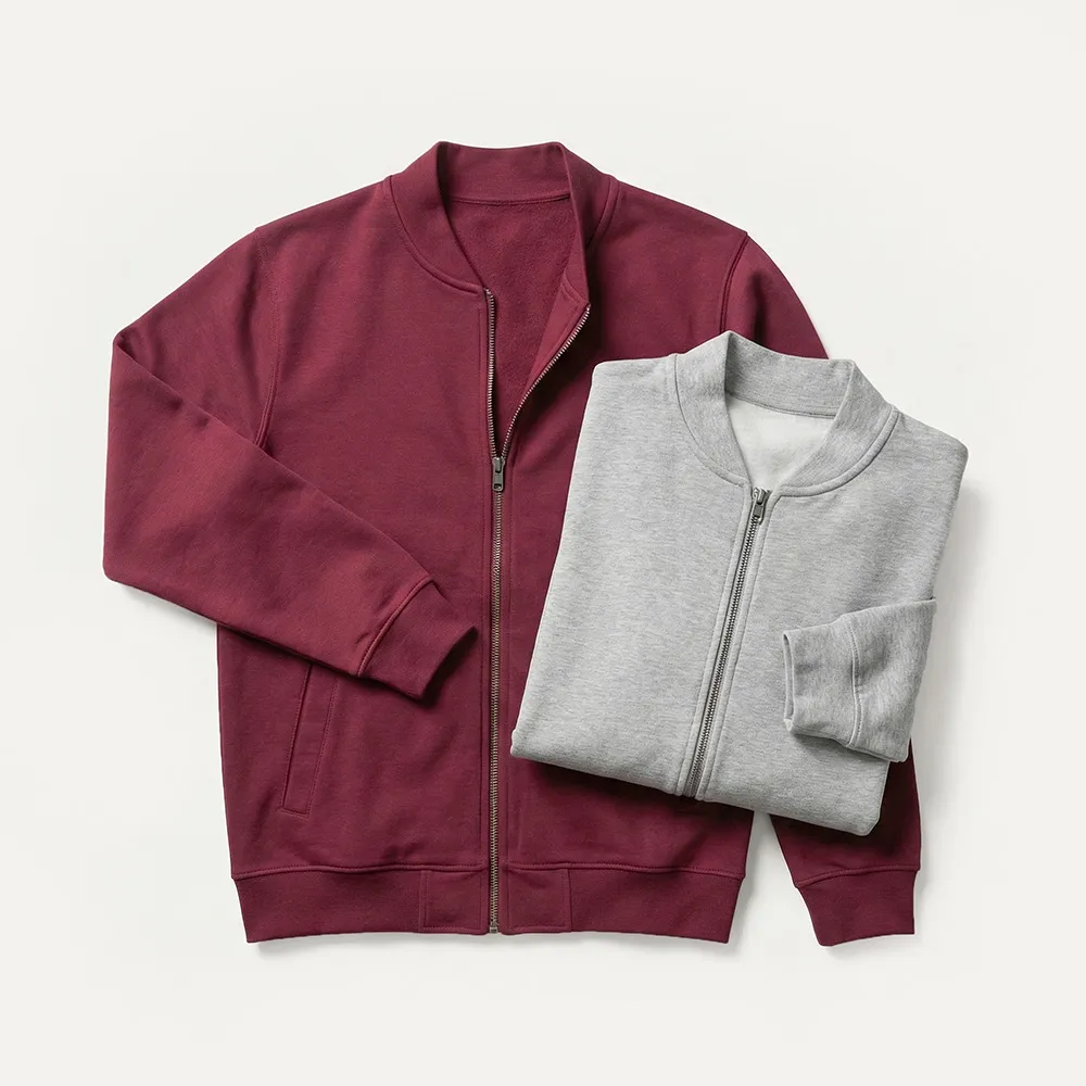 Eine weinrote Jacke mit Reißverschluss und eine gefaltete graue Jacke mit Reißverschluss auf weißem Hintergrund.