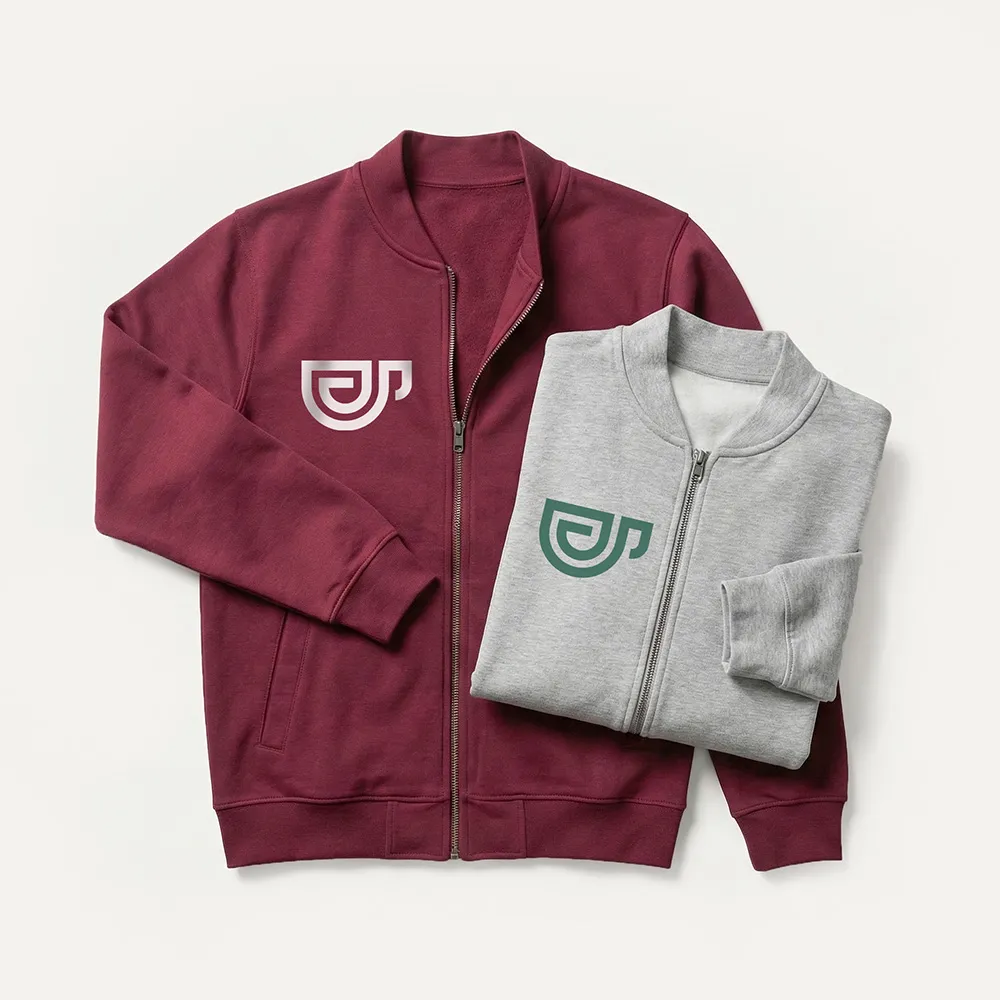 Zwei Jacken mit Reißverschluss, eine bordeauxrote flach ausgelegt und eine graue gefaltet darauf, beide mit einem stilisierten Logo auf der Brust.