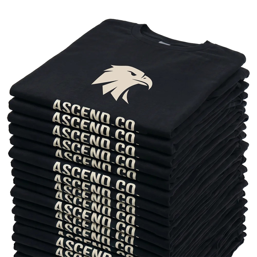 Gestapelte schwarze T-Shirts mit einem Adlerkopf und der Aufschrift Ascend Co.