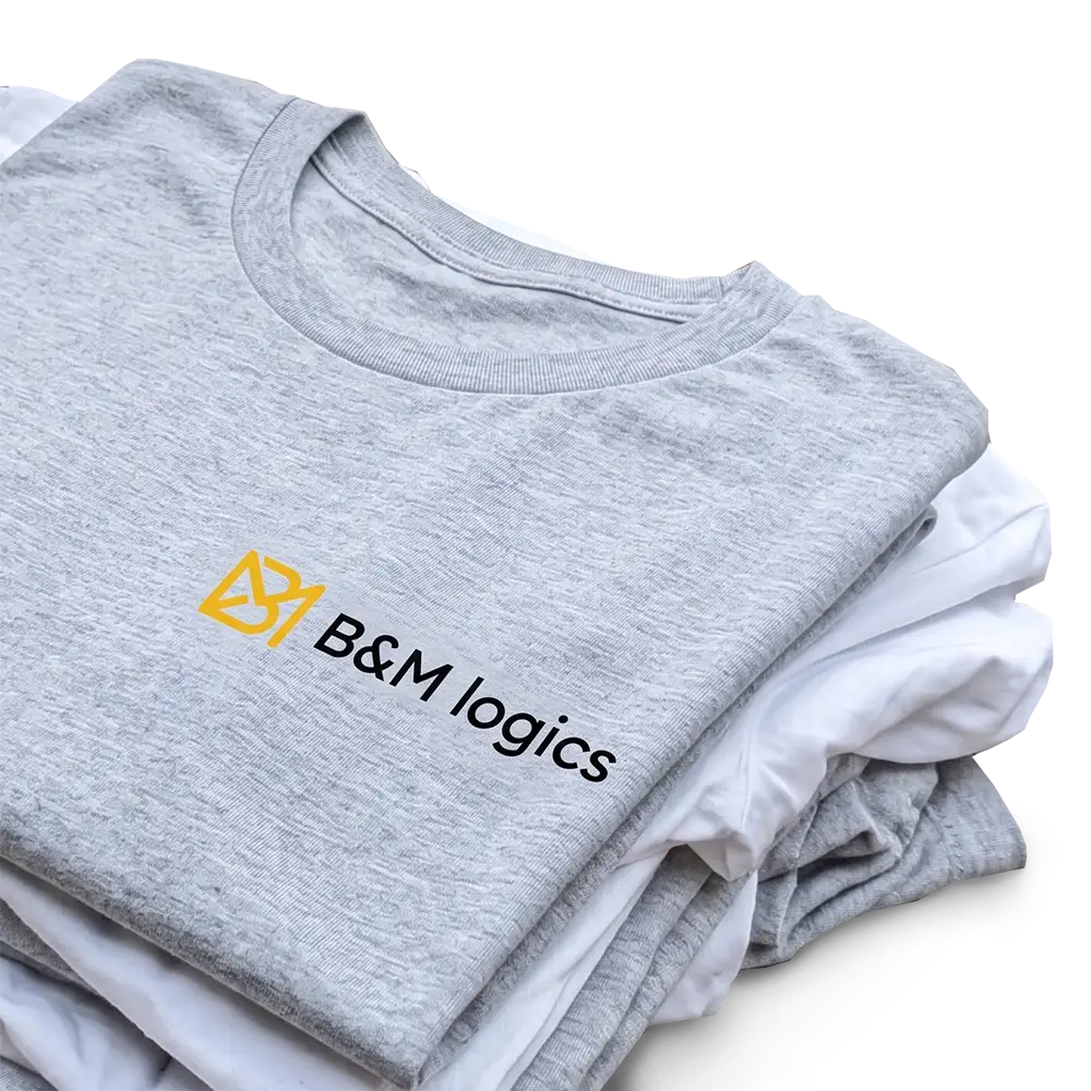 Gefalteter grauer Pullover mit gelbem B&M Logics-Logo auf einem Stapel weißer T-Shirts.
