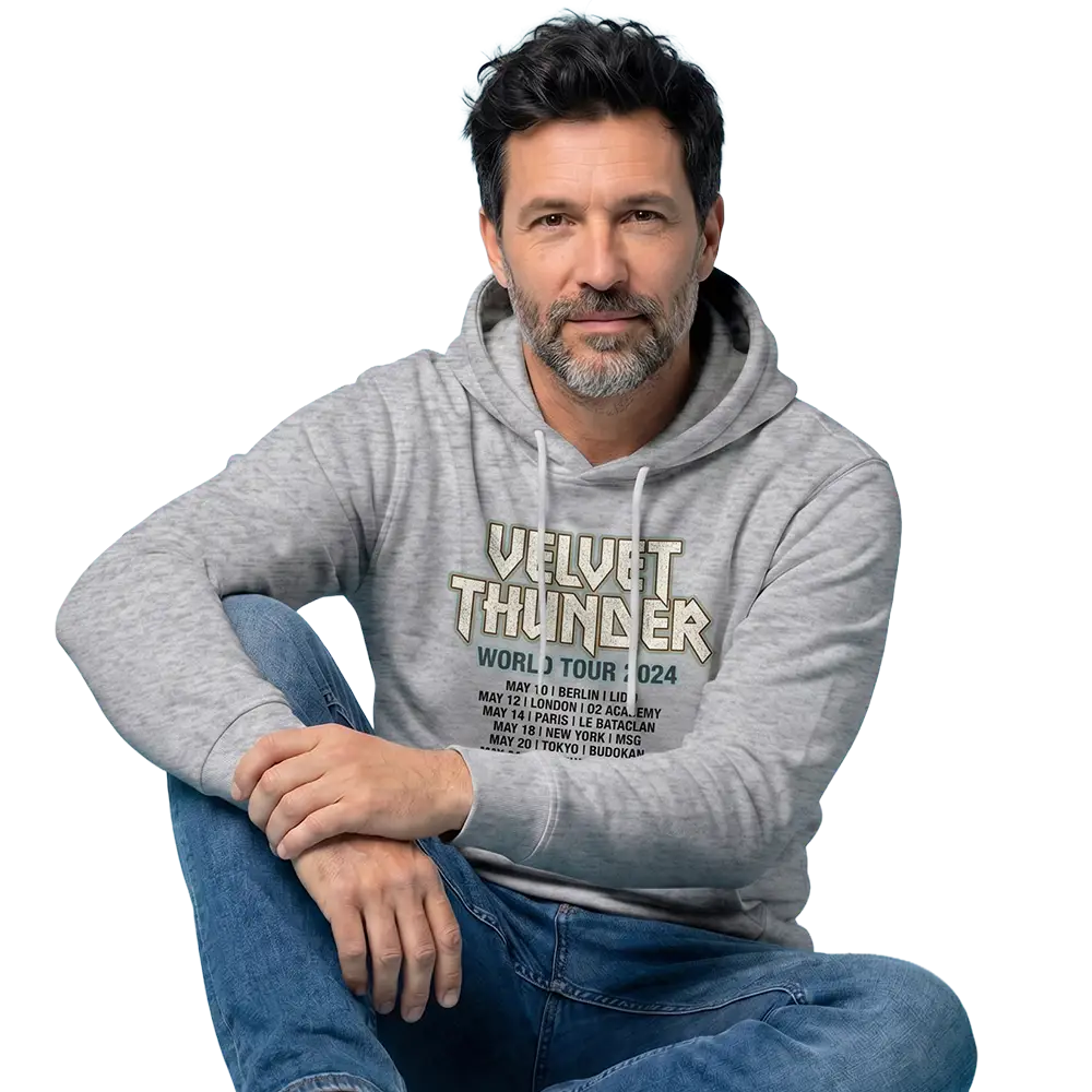 Mann sitzt mit verschränkten Armen auf Jeans, trägt grauen Hoodie mit Velvet Thunder Tour 2024-Aufdruck.