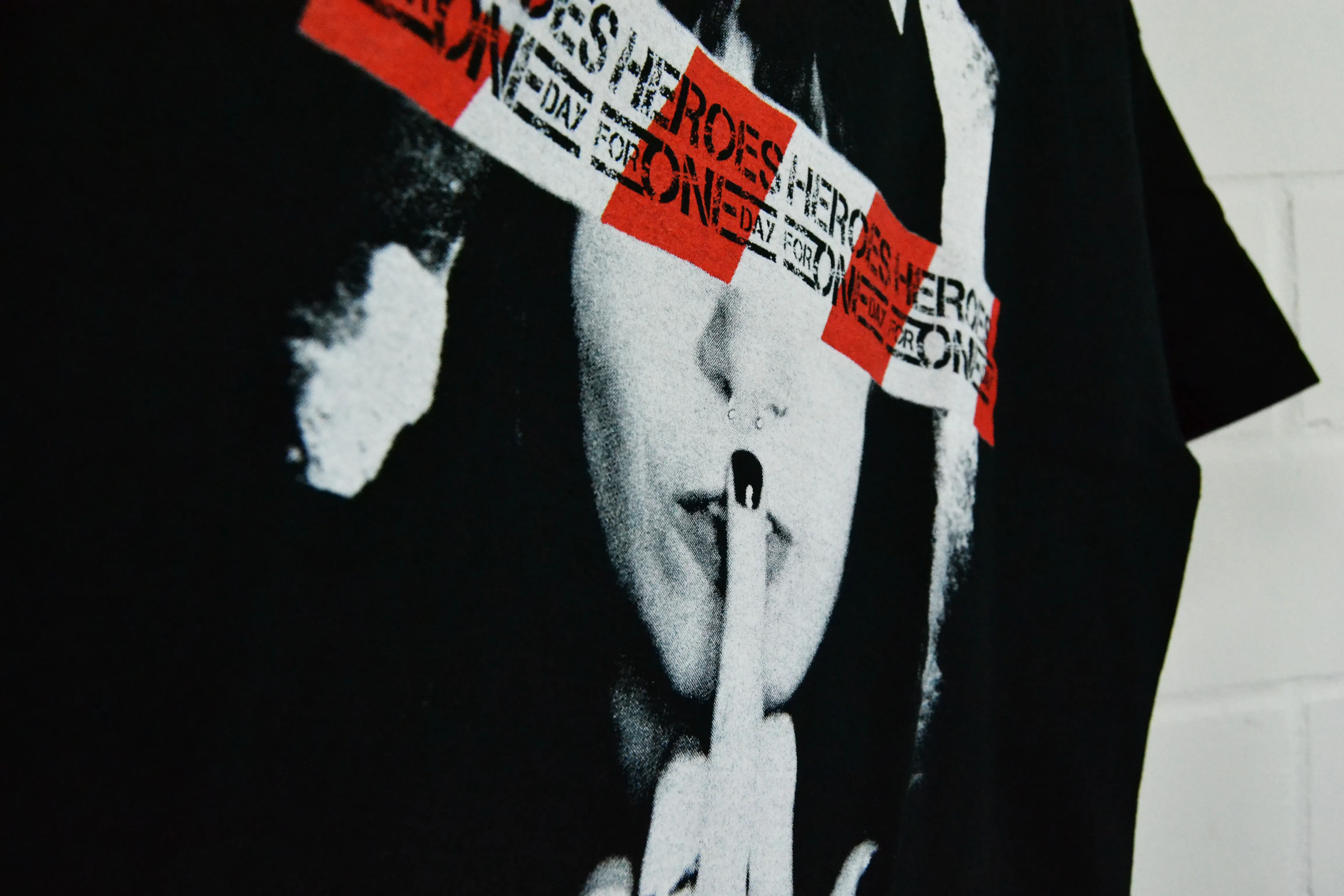 Nahaufnahme eines schwarzen Bandshirts mit Schwarz-Weiß-Fotomotiv und roten Textbalken