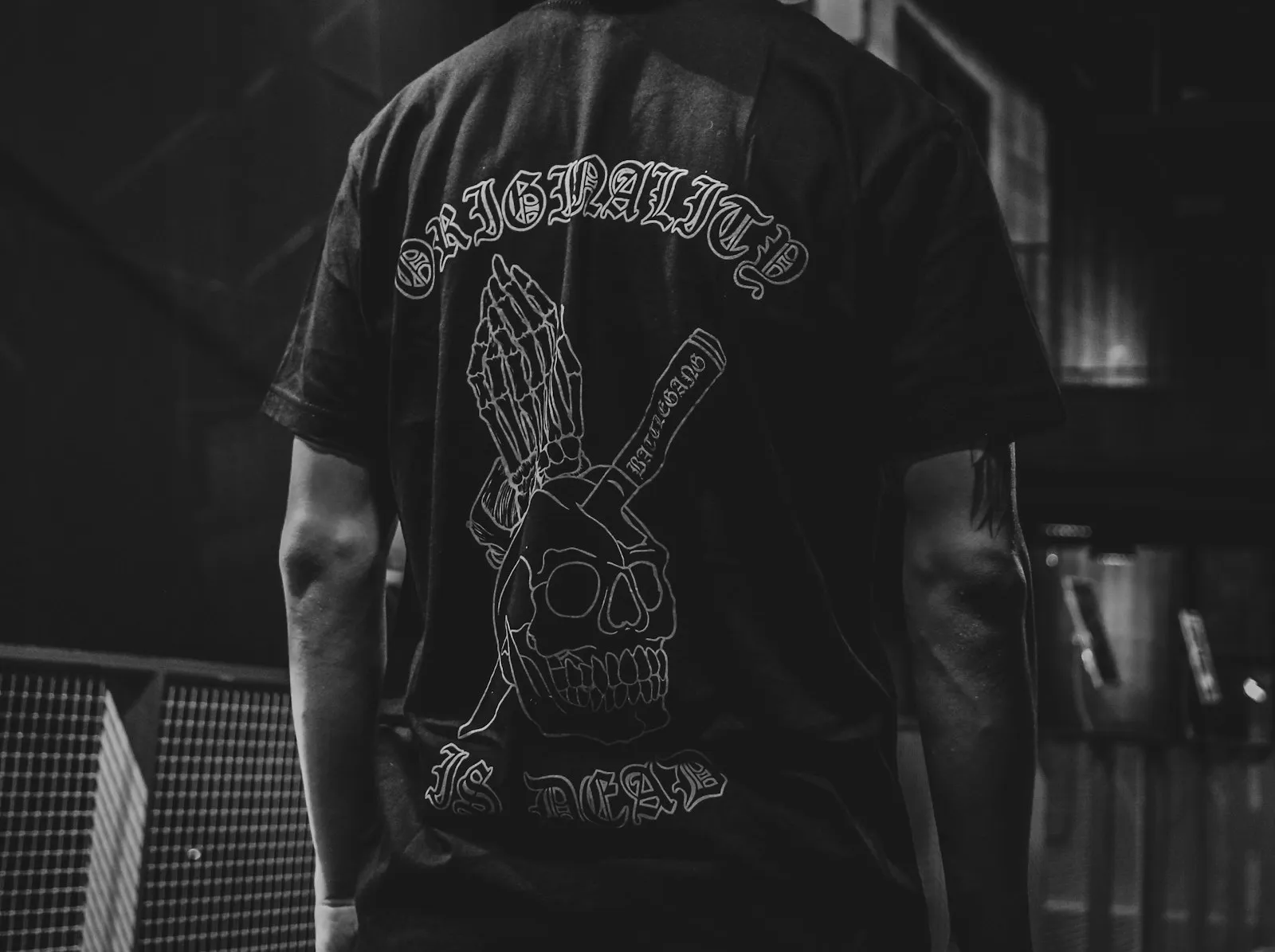 Person von hinten in schwarzem T-Shirt mit großem weißem Rückendruck im Club