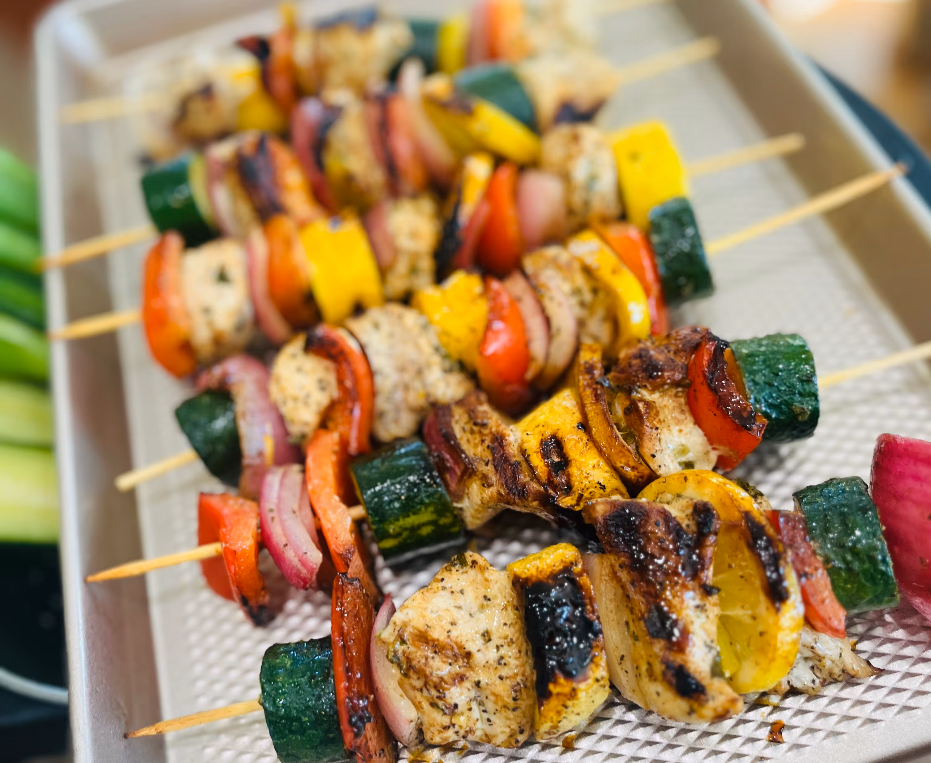 Close-up of five wooden skewers loaded with a variety of charred vegetables, showcasing bright colors and a caramelized finish.