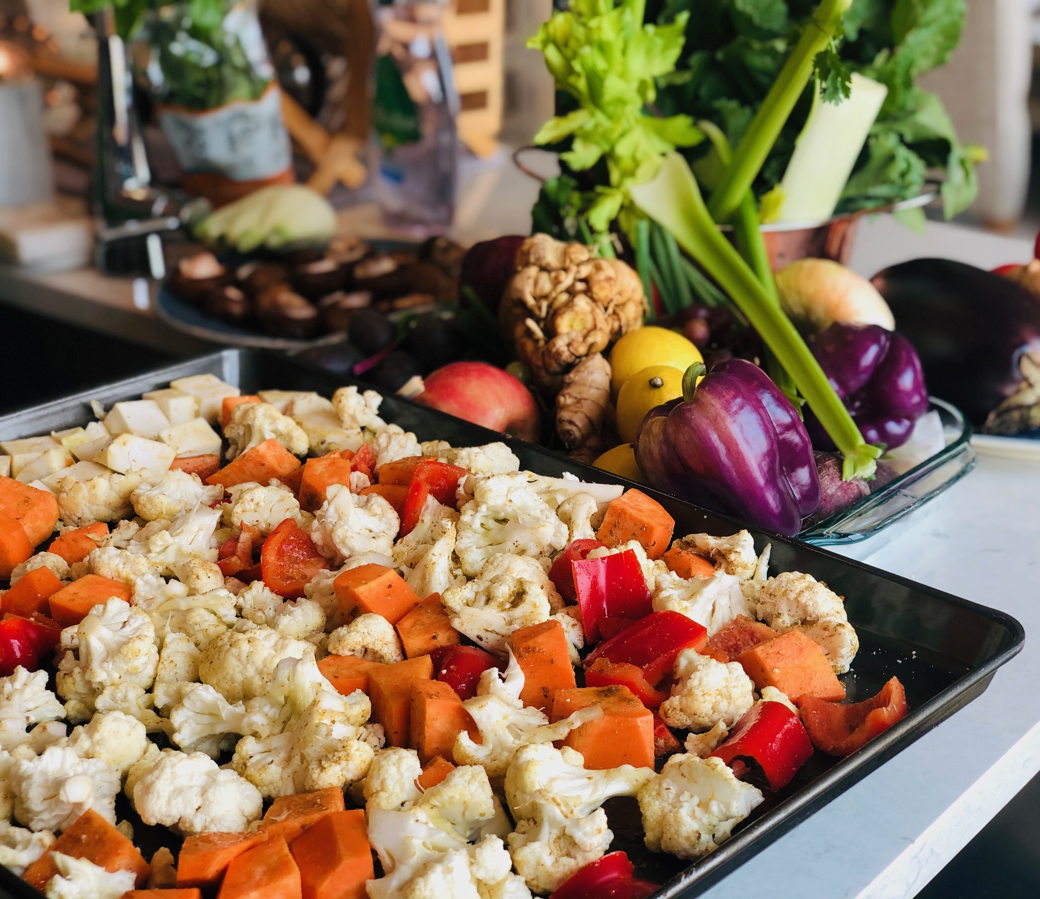 A vibrant, overhead arrangement of seasonal farm-to-table vegetables, including red and yellow peppers, broccoli, carrots, cherry tomatoes, cucumbers and cauliflower.