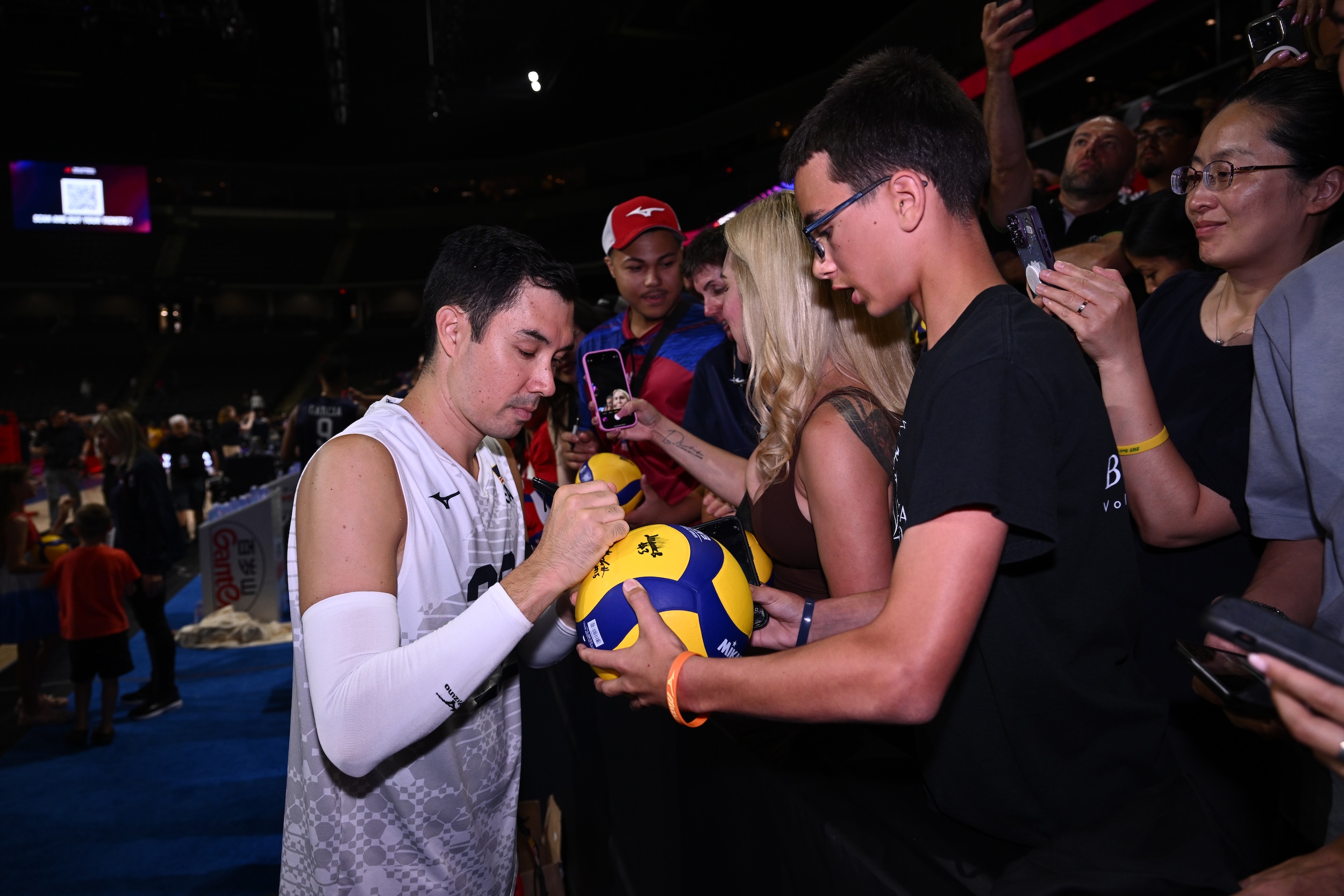 Volleyball player signing ball for fan