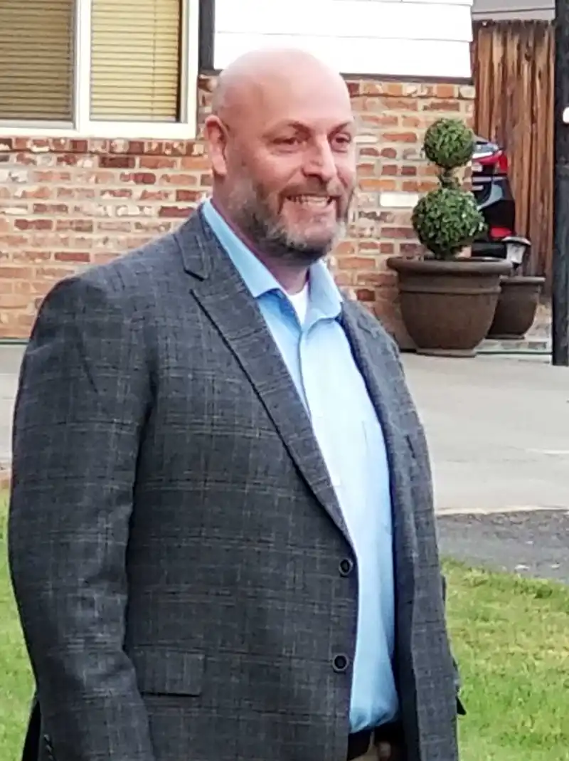 Cray Campbell smiling at camera wearing a professional grey suit with blue collard shirt.