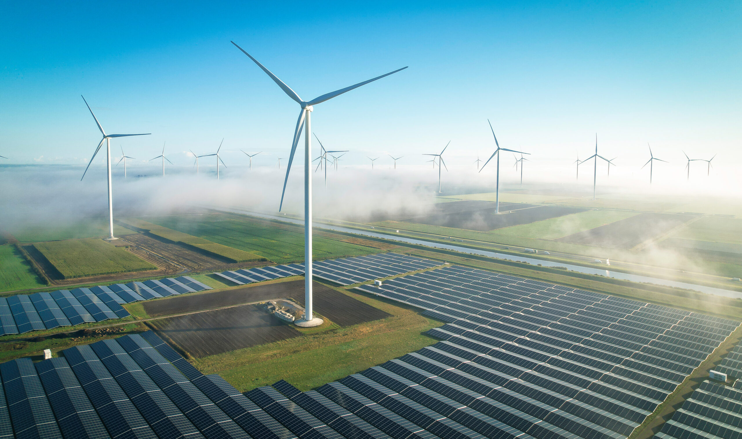 A wind turbine in a field surrounded by solar panels