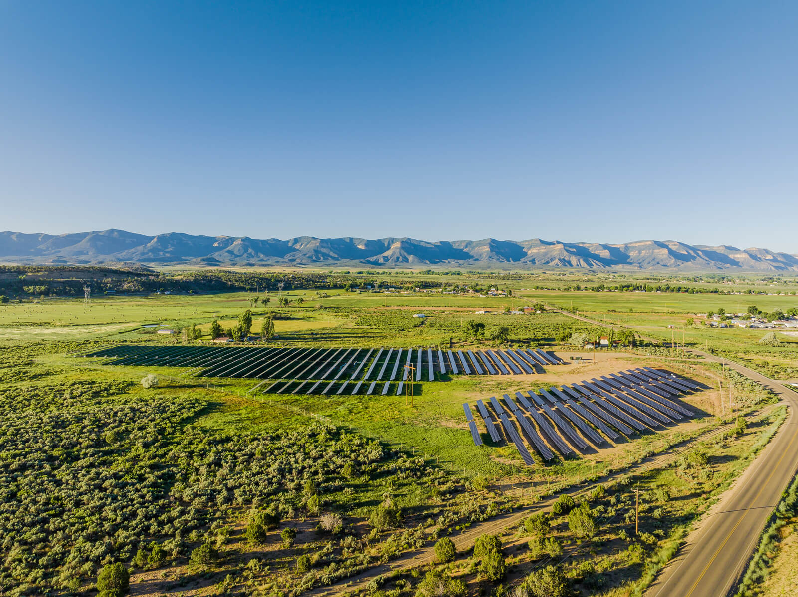 Far away shot of dozens of rows of solar panels in a valley