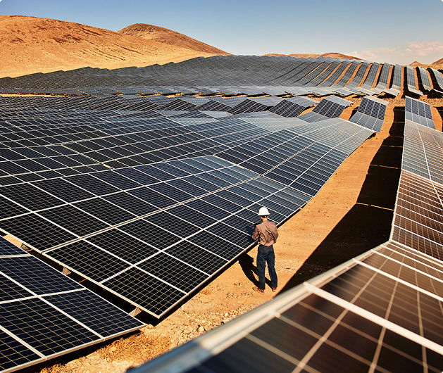 A worker inspecting solar panels in a desert