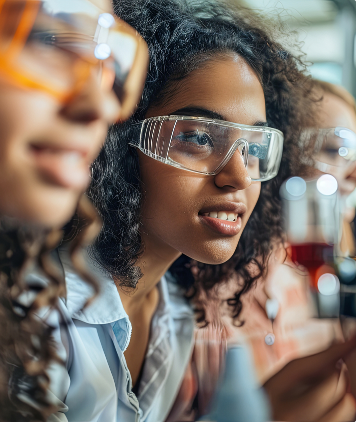 Girls conducting a science experiment with safety glasses on