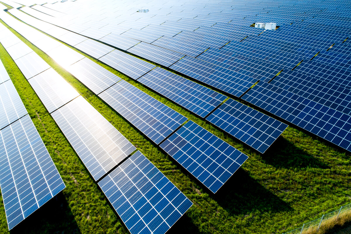 An aerial view of the sun shining on rows of solar panels