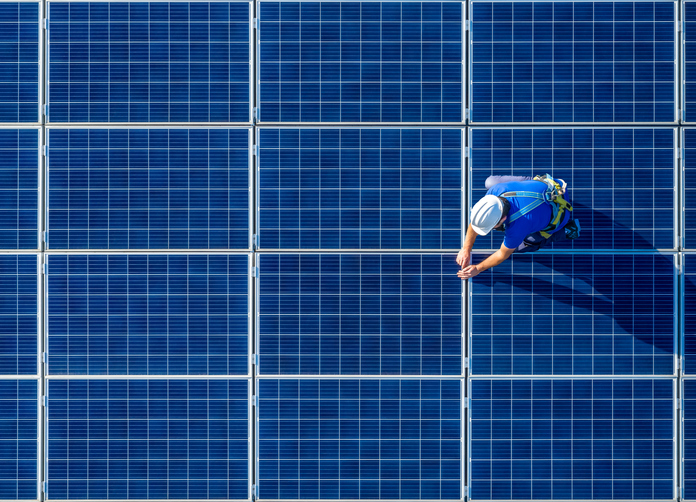 An aerial view of a worker standing on a solar panel while working on it