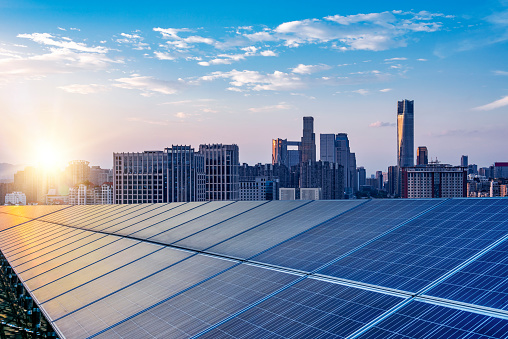 Solar panels on a roof with a city skyline in the background