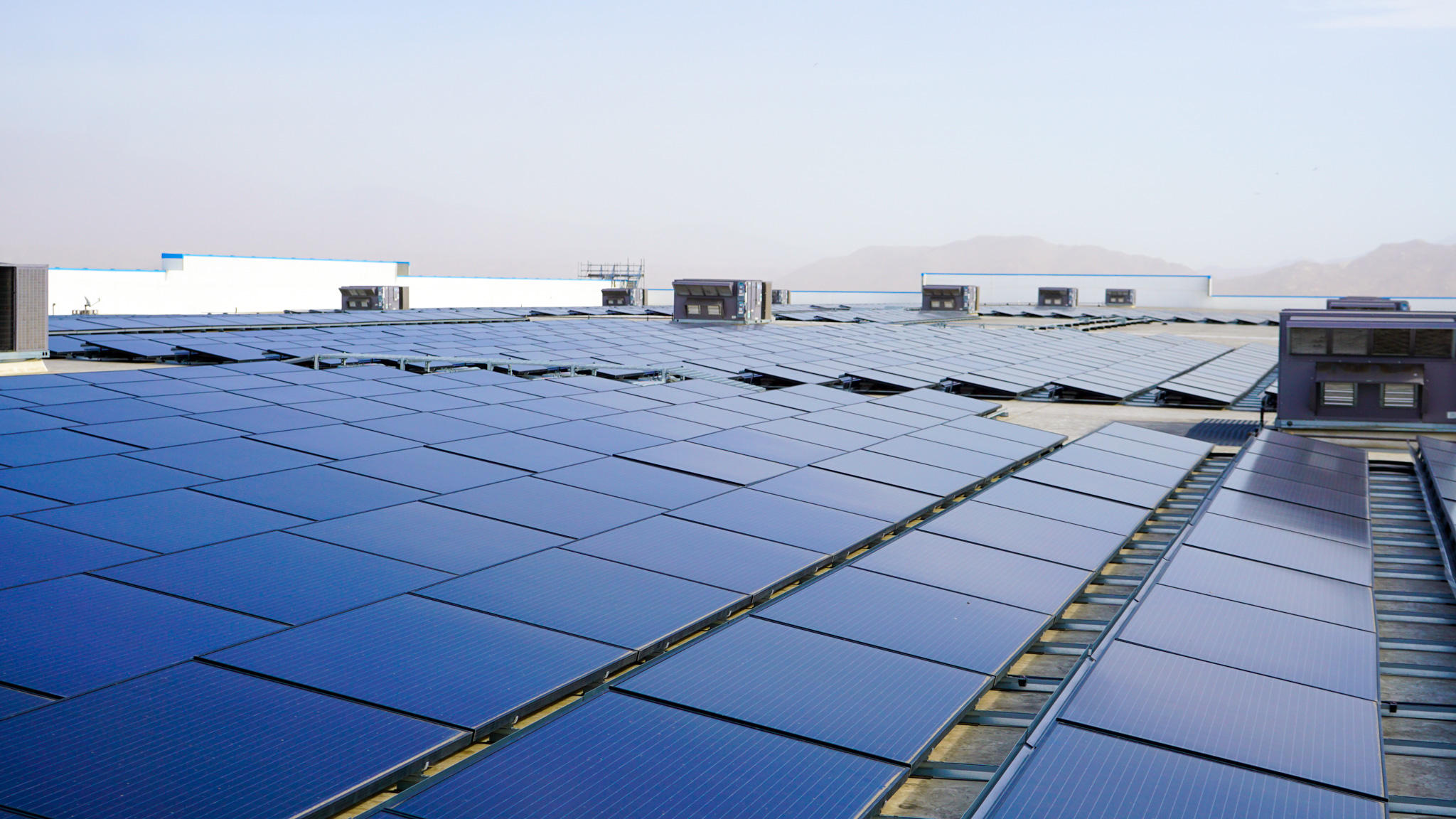 Side angle of solar panels on a roof with a mountain ridge in the background