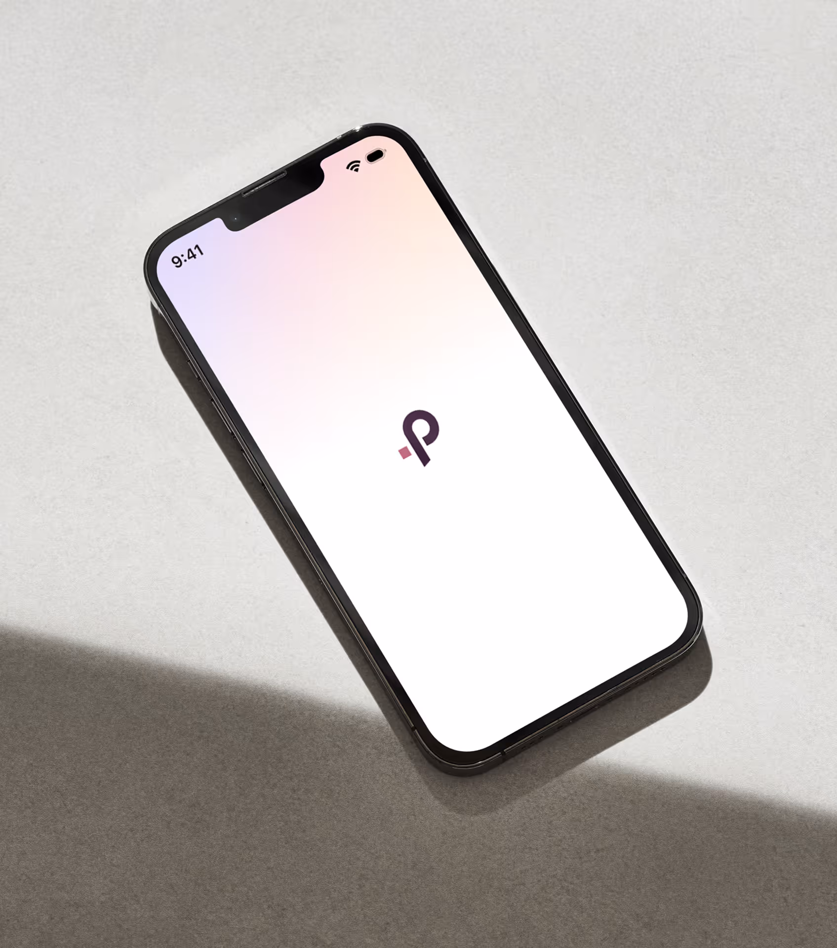 Smartphone lying on a light surface displaying a minimalist app loading screen with a black and purple logo in the center.
