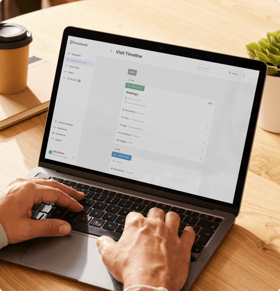 Person typing on a laptop displaying a medical records app with a visit timeline for radiology and laboratory sections.