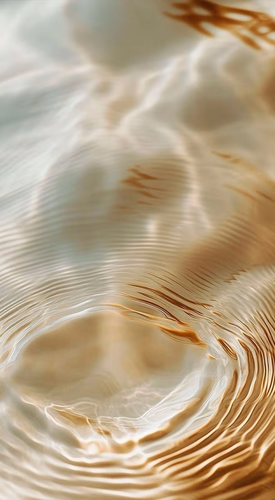 Close-up of water surface with light ripples and golden reflections creating a wavy pattern.
