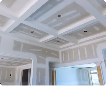 Unfertige Gipskartonwände und abgehängte Decke mit sichtbaren Spachtelstellen in einem hellen Raum.