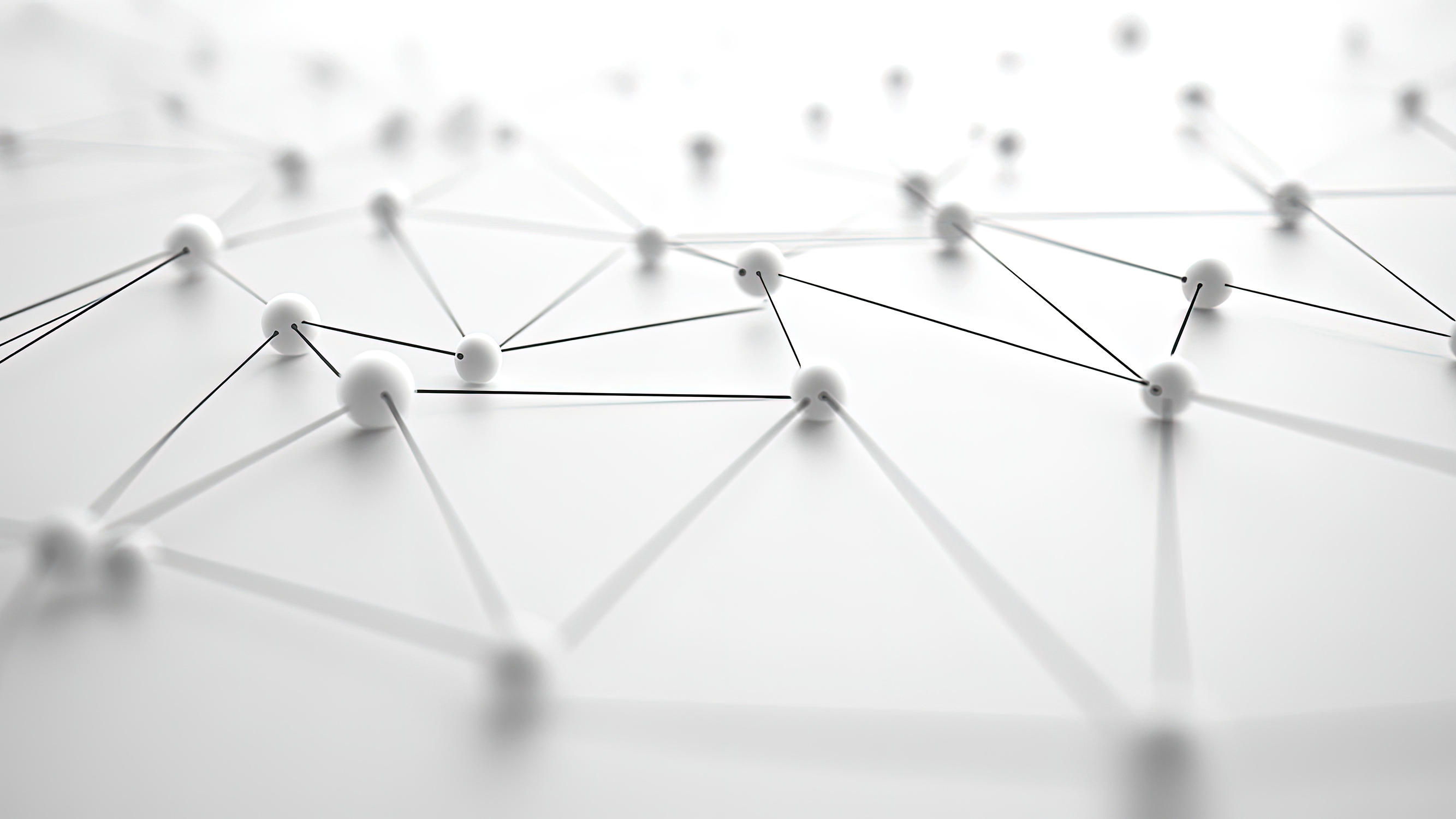 Close-up of white spheres interconnected by thin black lines forming a geometric network on a white surface.