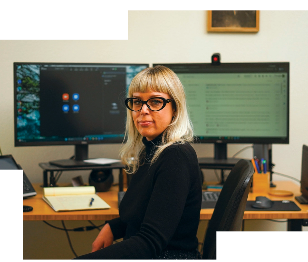 Woman sitting at computer desk looking at camera