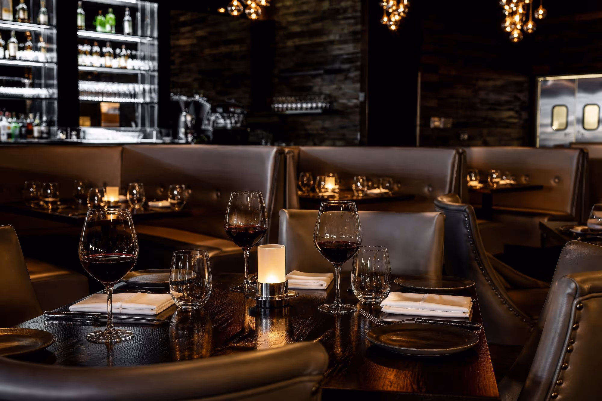 Partage Restaurant Las Vegas interior table settiing with wine glasses and bar in the background