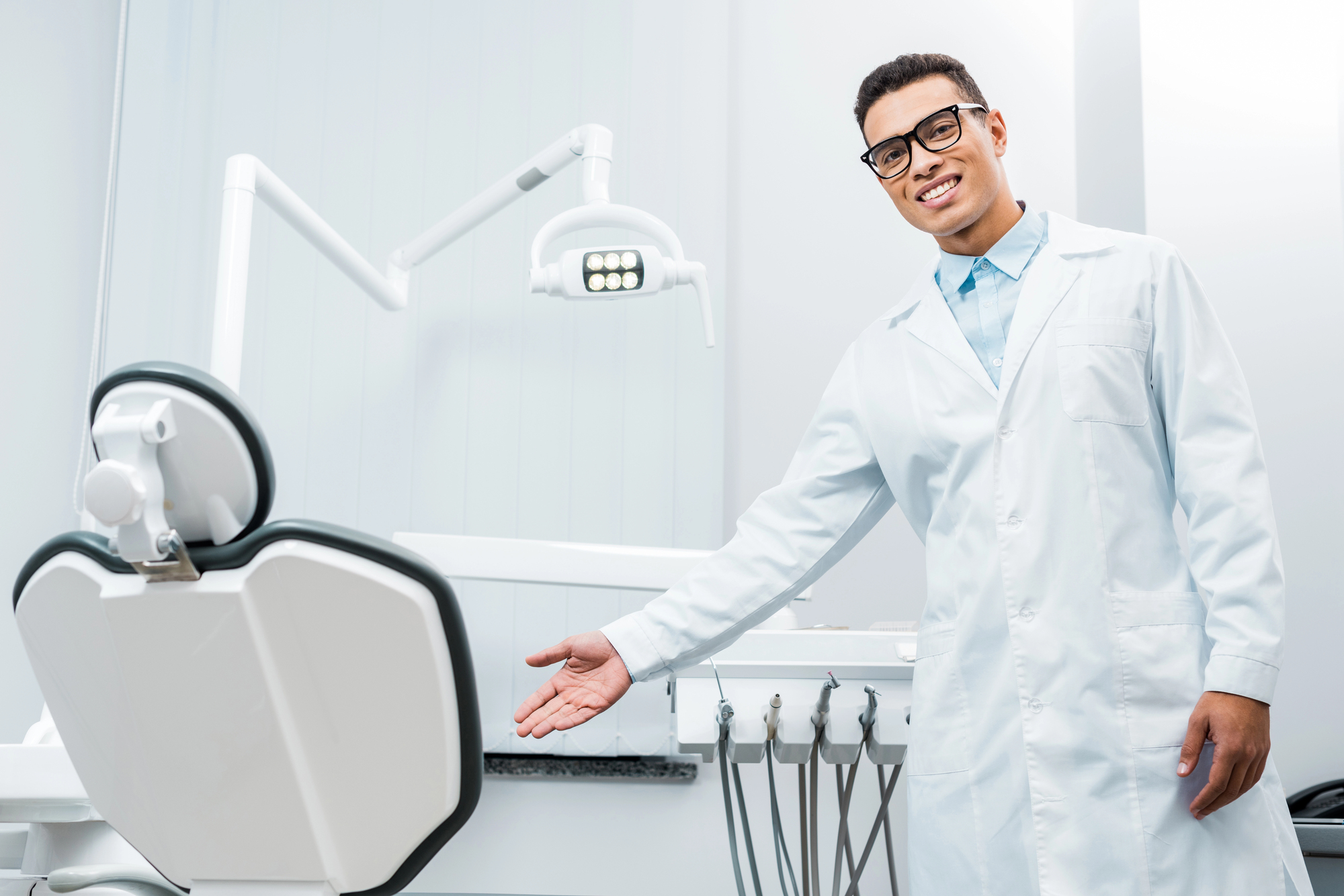 male dentist smiling next to dental chair