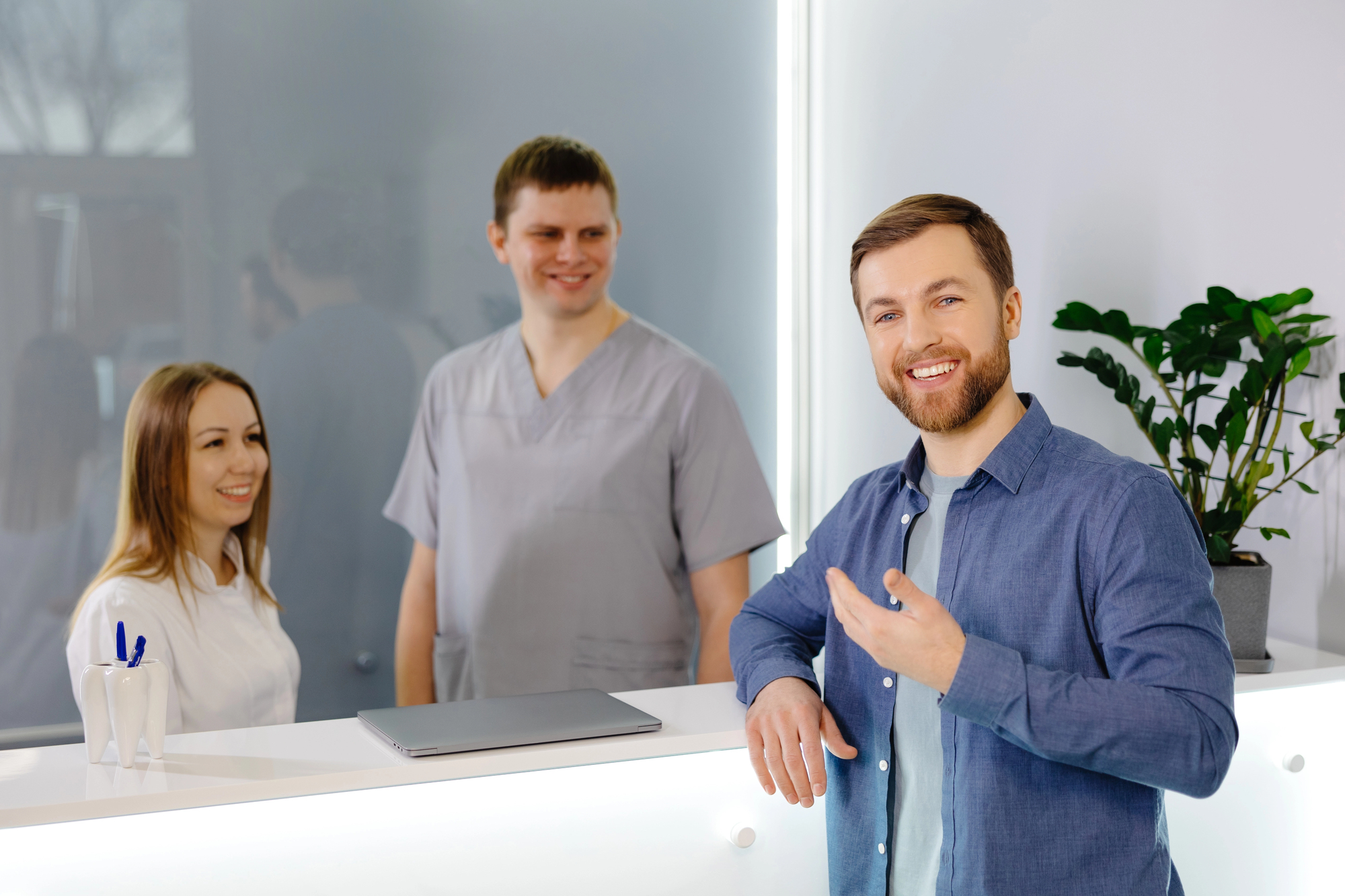 man at a front desk smiling with man and woman
