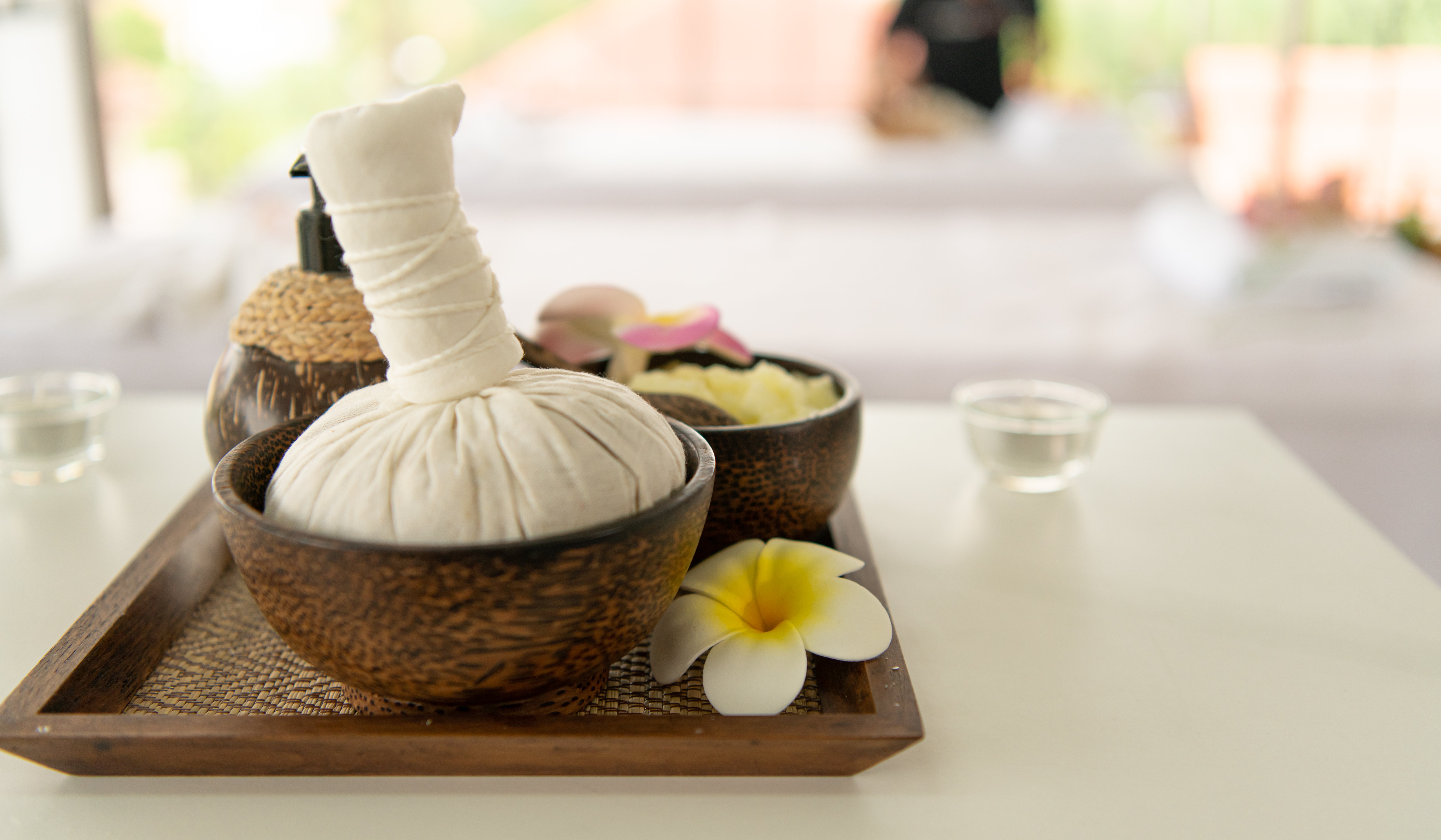 Traditional Ayurvedic spa setting with herbal compress, oils and frangipani flowers