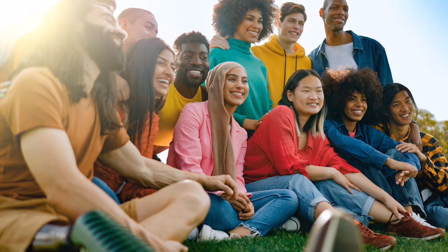 Group of friends sitting on grass smiling for picture