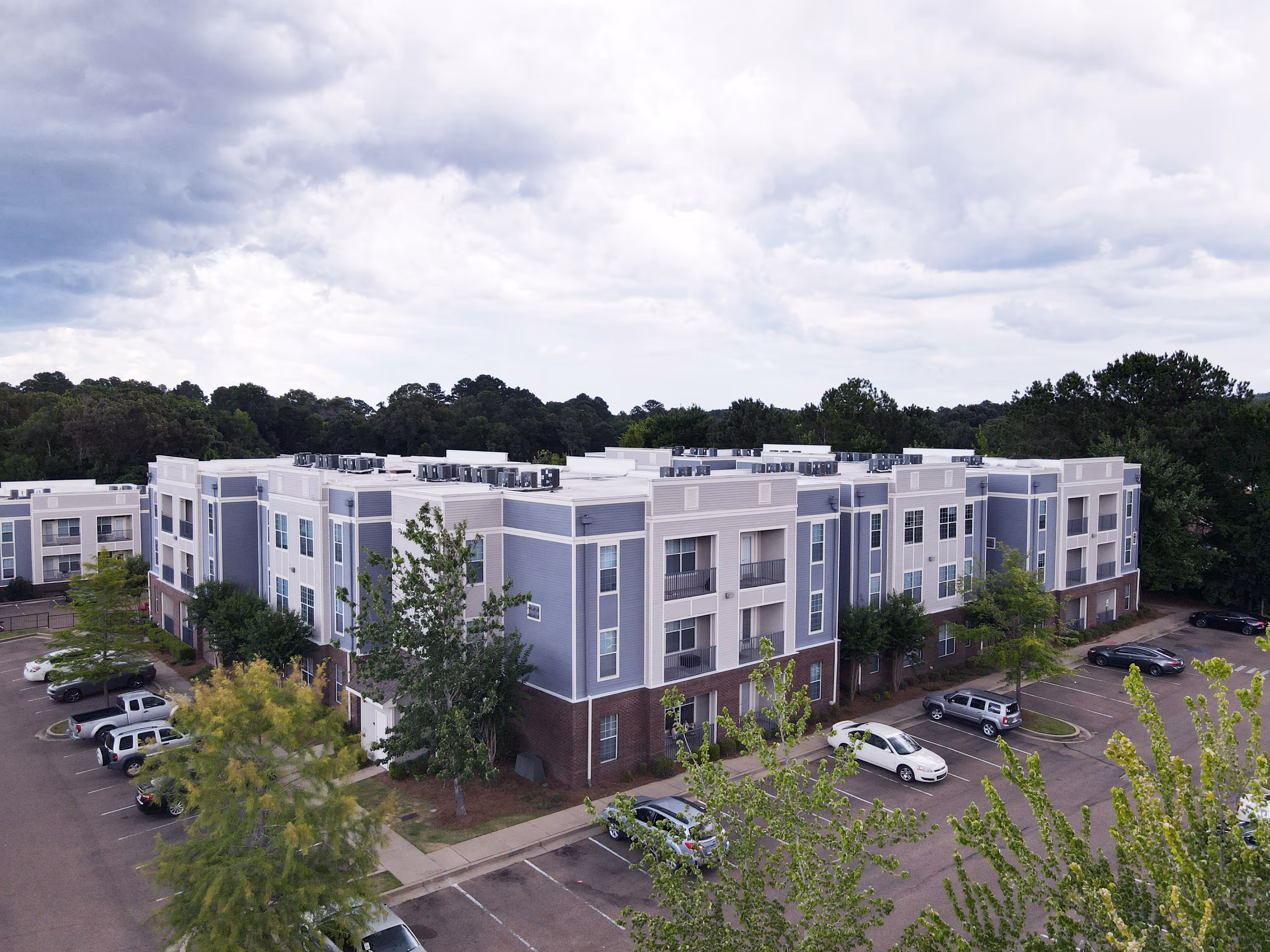 Aerial view of the Rev Oxford apartment community buildings and parking areas, surrounded by mature trees in Oxford, MS.