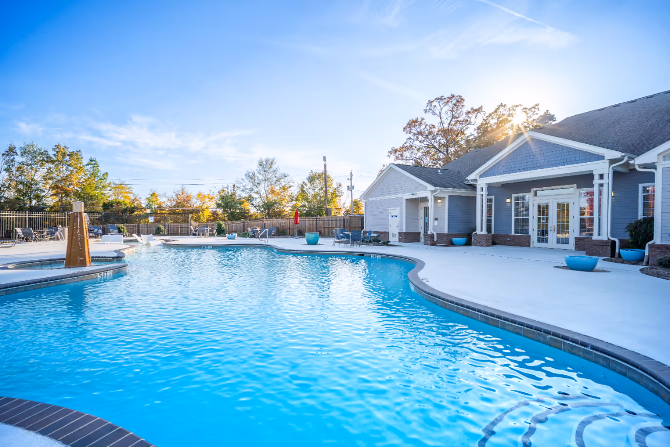 Resort-style swimming pool and sun deck with lounge chairs and the modern gray apartment buildings in the background at Rev Oxford in Oxford, MS.