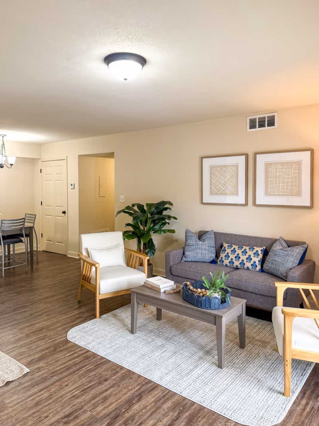 Apartment living room with a dark gray sofa, gray rug, and contemporary wall art, showcasing a home interior at Rev Oxford in Oxford, MS.