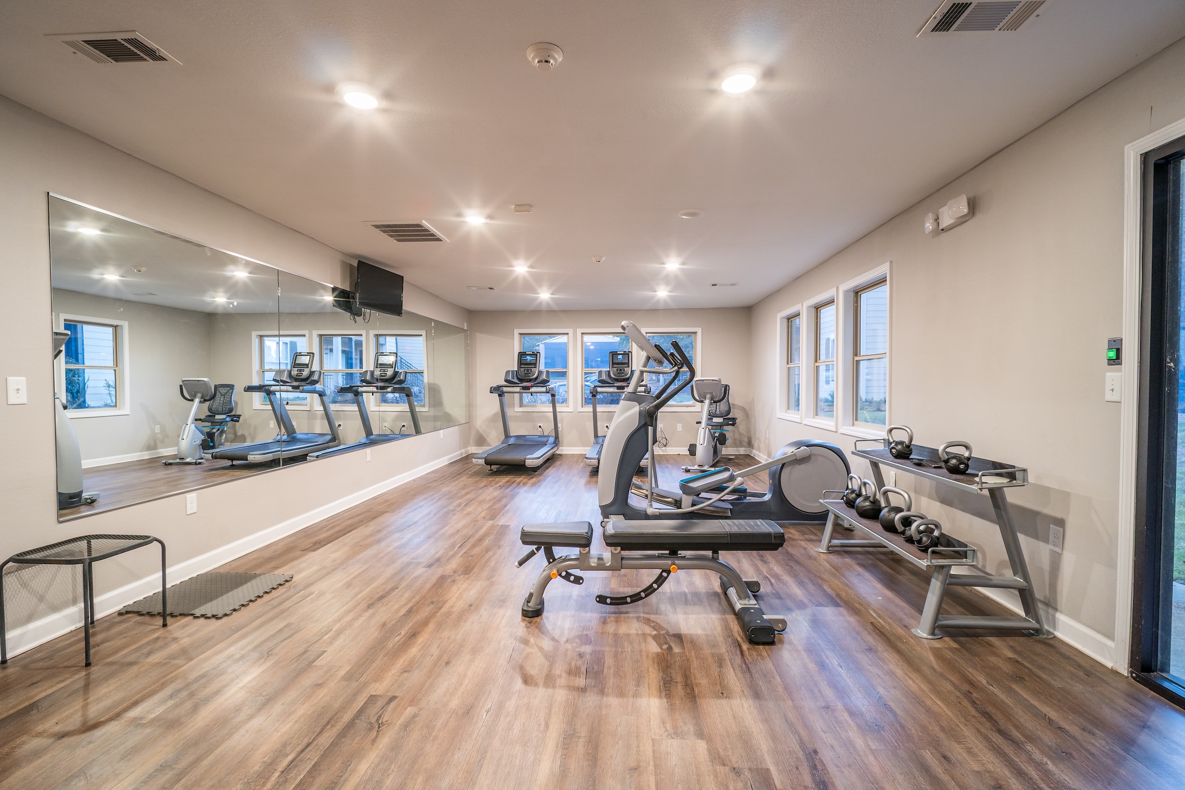 State-of-the-art fitness center with weight training equipment, mirrored walls, and rubber flooring, a key amenity at Rev Oxford in Oxford, MS.