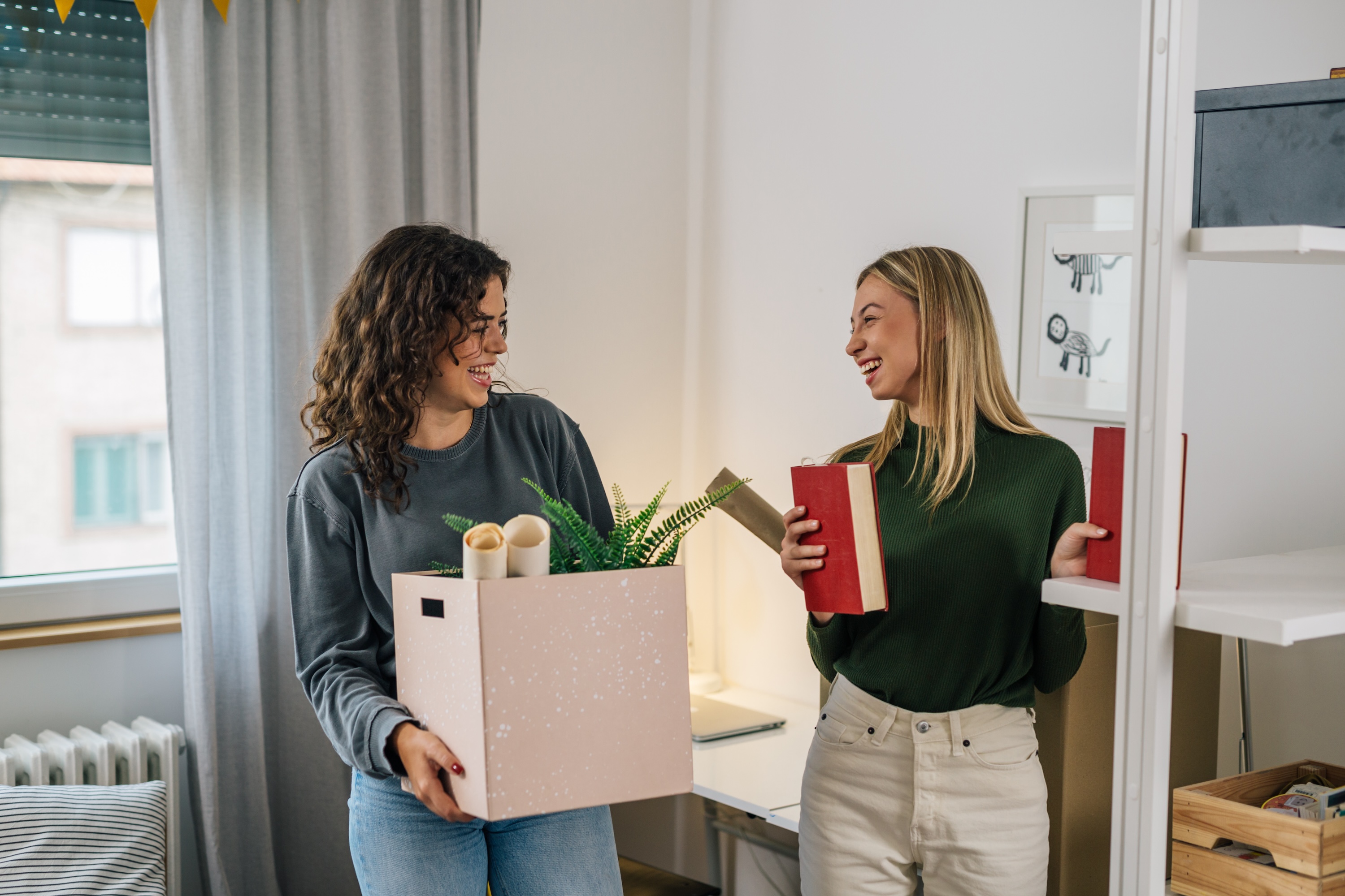 Residents smiling and unpacking books inside an apartment in Oxford, MS.