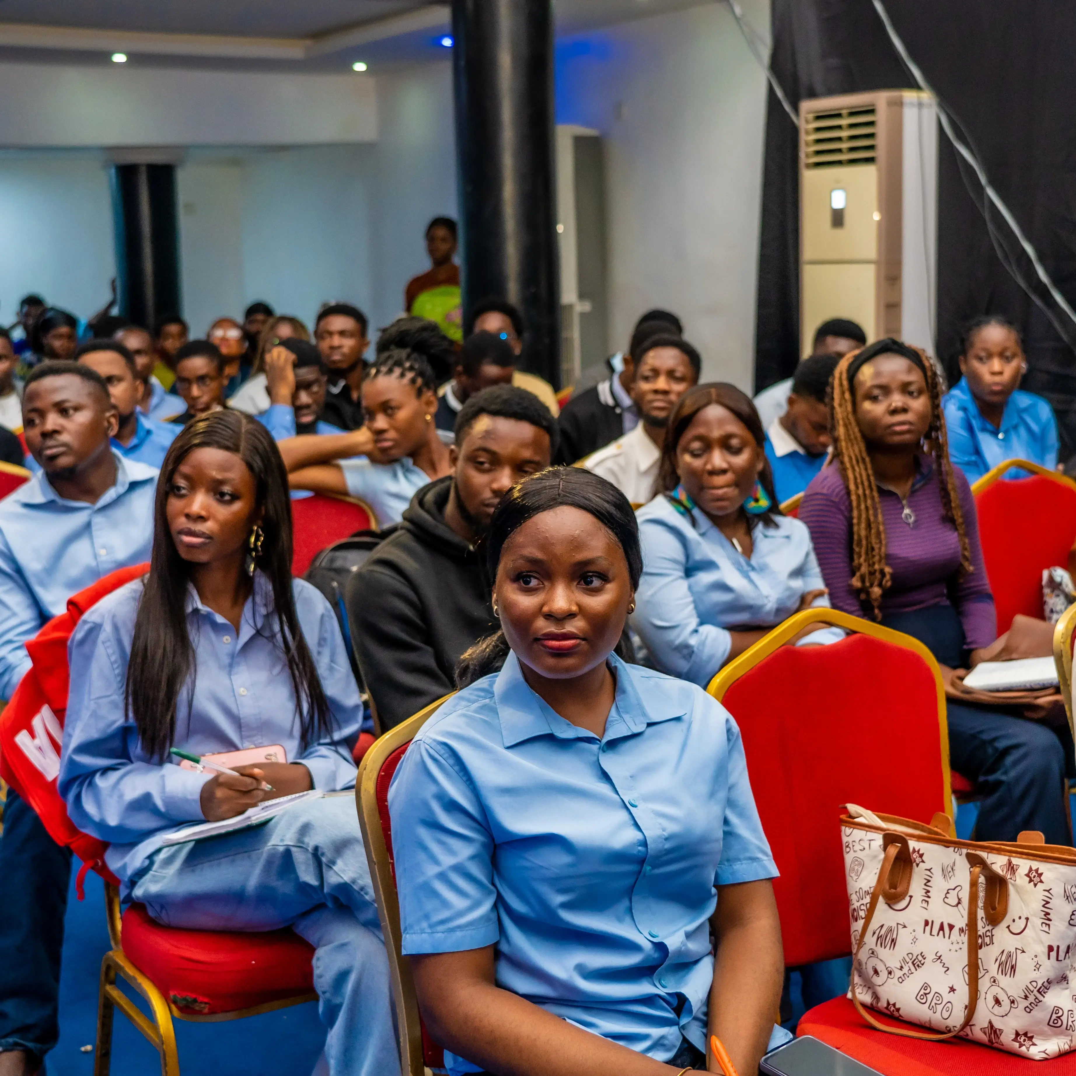 Group of attentive young adults seated in a seminar or classroom setting.