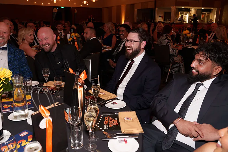 Black Friday Ball attendees listening to speeches on stage that is out of frame. 
