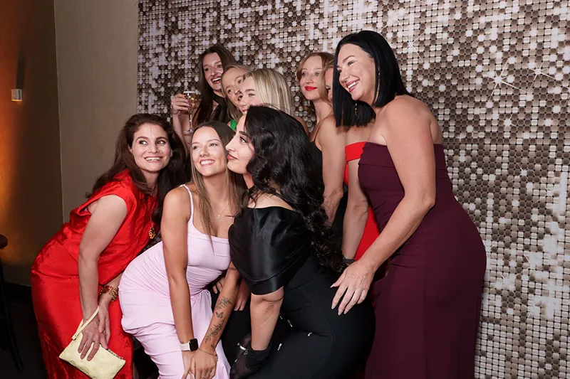 Group of people posing for photo in front of silver photobooth backdrop. 