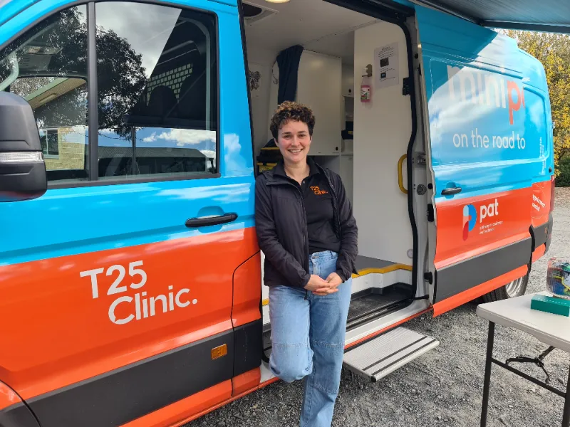 Person posing in doorway of blue and red T25 van.