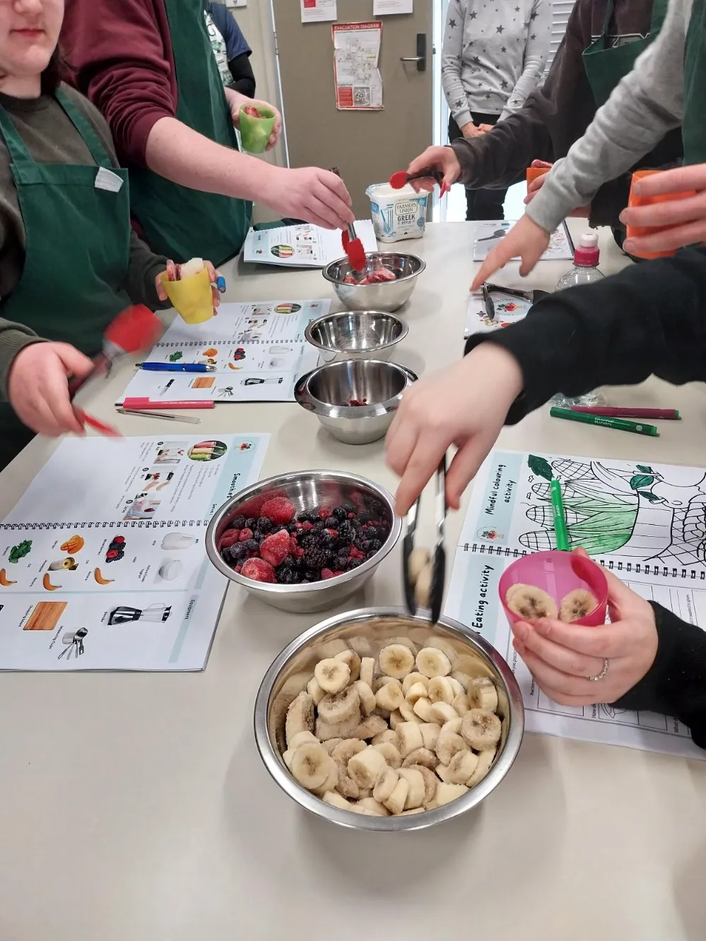Table of bowls of food with students hands reaching for. 